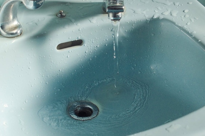 Grifo de lavabo antiguo mostrando un flujo hídrico deficiente y estancamiento inicial por problemas de caudal por poca presión y drenaje en Tenerife.