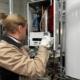 Técnico de Multiservice A.D. con guantes de protección realizando el ajuste de los circuitos electrónicos de un calentador para verificar su correcto arranque térmico.