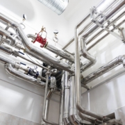 Complejo entramado de fontanería industrial con tuberías de acero inoxidable, manómetros de presión y válvulas de cierre en una sala técnica impecable. Complejo entramado de fontanería industrial con tuberías de acero inoxidable, manómetros de presión y válvulas de cierre en una sala técnica impecable.