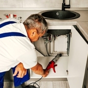 Operario cualificado utilizando una máquina para desatascos electromecánica de espiral en el desagüe bajo fregadero. Operario cualificado utilizando una máquina para desatascos electromecánica de espiral en el desagüe bajo fregadero.