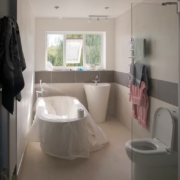 Baño residencial finalizado tras la reforma, mostrando mampara de cristal, lavabo de columna, inodoro y bañera desembalada. Baño residencial finalizado tras la reforma, mostrando mampara de cristal, lavabo de columna, inodoro y bañera desembalada.