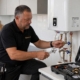 Fontanero de Multiservice A.D. ajustando las válvulas y racores de latón de un termo eléctrico con maletín de herramientas en Tenerife Sur.
