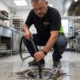 Técnico de Multiservice A.D. introduciendo manguera hidrodinámica de alta presión en el sumidero de una cocina industrial en Tenerife Sur.