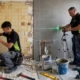 Técnicos de Multiservice A.D. replanteando tuberías de lavabo y nivelando alicatado con láser en un baño en obras.